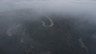 AX44_029E - 4K aerial stock footage of winding roads in fog, Hollywood Hills, California, sunset