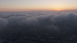 AX44_035 - 4K aerial stock footage flying above thick marine layer, Hollywood, California, sunset