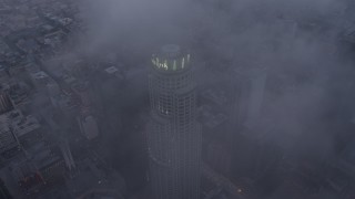AX44_036E - 4K aerial stock footage fly over the city covered in fog, tilt to reveal skyscraper in Downtown Los Angeles, California, twilight