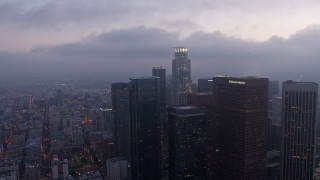 AX44_050 - 4K aerial stock footage orbiting skyscrapers and high-rises below marine layer, Downtown Los Angeles, twilight