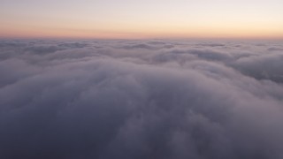 AX44_055 - 4K aerial stock footage flying over marine layer, Los Angeles twilight