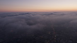 AX44_056 - 4K aerial stock footage flying over marine layer, Los Angeles, twilight