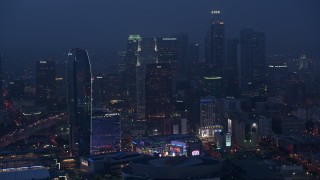 AX44_062 - 4K stock footage aerial video tilting up from the interstates revealing Downtown skyline, Los Angeles, twilight