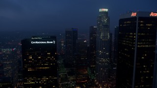 AX44_065E - 4K aerial stock footage tilting up from city streets revealing skyscrapers, Downtown Los Angeles, twilight