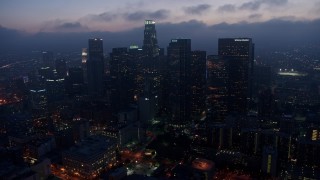 AX44_068E - 4K aerial stock footage approaching Downtown Los Angeles skyline below marine layer, twilight