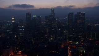 AX44_073 - 4K aerial stock footage flying by skyscrapers below marine layer, Downtown Los Angeles, twilight