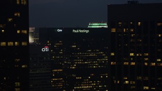 AX44_076E - 4K aerial stock footage of flying by skyscrapers with lights in the windows, Downtown Los Angeles, twilight