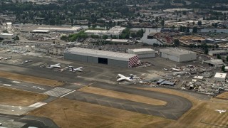 AX45_012 - 5K aerial stock footage flying by airliners parked by a hangar at Boeing Field, Seattle, Washington, as a smaller plane lands