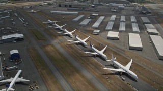 AX46_003 - 5K stock footage aerial video approach and fly over a row of parked airliners, Paine Field, Washington