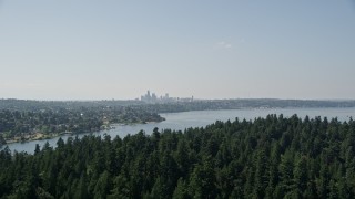 AX47_005 - 5K aerial stock footage fly over tree covered Bailey Peninsula to reveal Downtown Seattle skyline, Washington