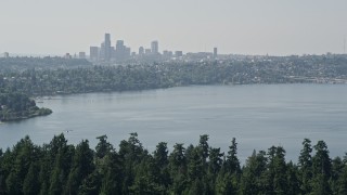AX47_007E - 5K aerial stock footage of Downtown Seattle skyline in the far distance beyond the tree-covered Bailey Peninsula, Washington