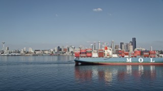 AX47_030E - 5K aerial stock footage flyby a cargo ship and tugboat sailing Elliott Bay to focus on the Downtown Seattle skyline, Washington