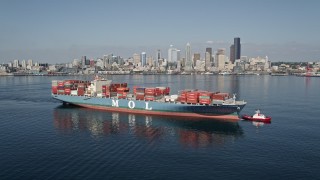 AX47_035 - 5K aerial stock footage flyby a cargo ship and tugboat with the Downtown Seattle skyline in the background, Washington