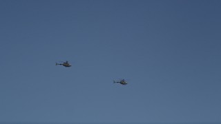 AX47_107E - 5K aerial stock footage of tracking two Kiowa Warrior helicopters over Downtown Seattle, blue skies, Washington