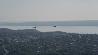 AX47_110E - 5K aerial stock footage of two Kiowa Warrior helicopters in flight over Seattle, Washington