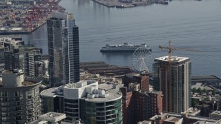 AX47_135E - 5K aerial stock footage of a ferry approaching the Central Waterfront, seen while flying over high-rises in Downtown Seattle, Washington