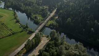 AX48_030 - 5K aerial stock footage fly over a green field to approach a small bridge spanning the Snoqualmie River in Carnation, Washington