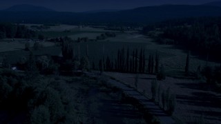 AX48_039_DFN - 4K day for night color corrected aerial stock footage of tall trees and the Snoqualmie River near crop fields in Carnation, Washington