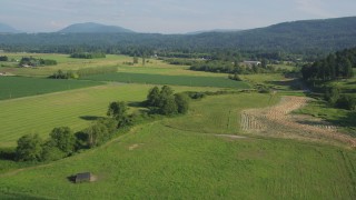 AX48_040 - 5K aerial stock footage fly over crop fields and a country road to approach a greenhouse in Carnation, Washington