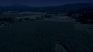AX48_040_DFN - 4K day for night color corrected aerial stock footage of crop fields and a country road near a greenhouse in Carnation, Washington