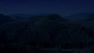 AX48_053_DFN - 4K day for night color corrected aerial stock footage of flying over a wooded mountain in King County, Seattle, Washington