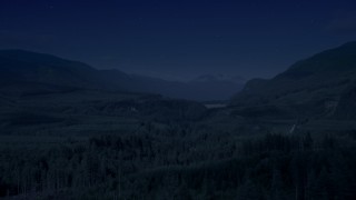 AX48_057_DFN - 4K day for night color corrected aerial stock footage of a forest and a narrow road through evergreen trees in King County, Washington