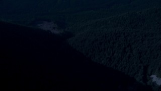 AX48_065_DFN - 4K day for night color corrected aerial stock footage of a bird's eye of a river through evergreen forest in the Cascade Range, Washington