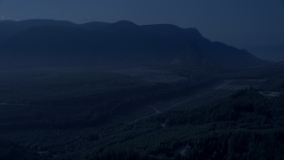 AX48_067_DFN - 4K day for night color corrected aerial stock footage of a forest road through newer forest growth area near the Cascade Range, King County, Washington