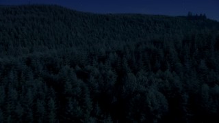 AX48_076_DFN - 4K day for night color corrected aerial stock footage of flying over dense evergreen forest in King County, Washington