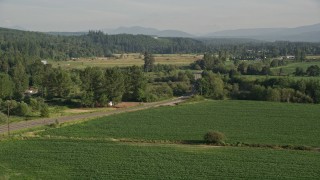 AX49_017 - 5K aerial stock footage of flying by a country road by a field of crops, Carnation, Washington