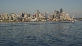 AX49_089E - 5K aerial stock footage of the Downtown Seattle skyline seen while flying low over Elliott Bay past a tugboat, Washington
