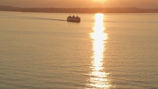 AX50_013E - 5K aerial stock footage of setting sun over a ferry sailing Elliott Bay, Washington, sunset