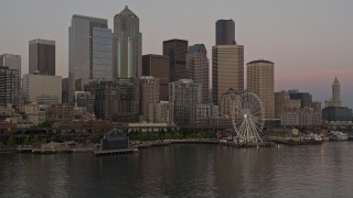 AX50_049E - 5K aerial stock footage of low approach to the Great Wheel and Waterfront, and the towering skyline of Downtown Seattle, Washington, sunset