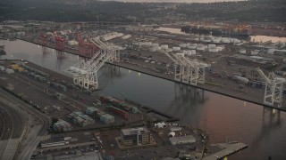 AX50_065 - 5K aerial stock footage of cargo cranes by the Duwamish Waterway, Harbor Island, Seattle, Washington, sunset