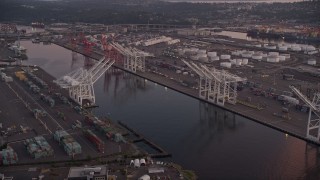 AX50_065E - 5K aerial stock footage of cargo cranes by the Duwamish Waterway, Harbor Island, Seattle, Washington, sunset