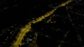 AX51_005 - 5K aerial stock footage of bird's eye of a brightly-lit road through dark suburban neighborhoods, Rainier Beach, Seattle, Washington, night