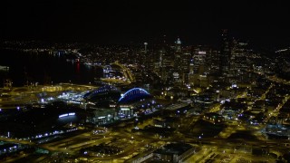 AX51_007E - 5K aerial stock footage approach Safeco and CenturyLink Fields, with a view of Downtown Seattle skyscrapers, Washington, night