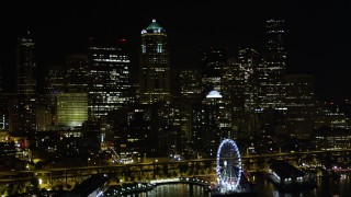 AX51_014 - 5K stock footage aerial video fly over Great Wheel and Central Waterfront to approach skyscrapers, Downtown Seattle, Washington, night