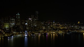 AX51_019E - 5K aerial stock footage of the Downtown Seattle skyline, Seattle Great Wheel, and Central Waterfront piers, Washington, night