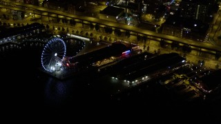 AX51_021E - 5K aerial stock footage of Waterfront piers, approach Seattle Great Wheel, Downtown Seattle, Washington, night