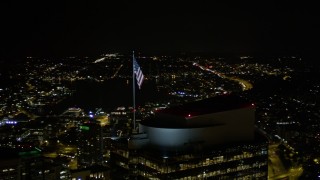 AX51_078E - 5K aerial stock footage orbit the American flag atop Two Union Square in Downtown Seattle, Washington, night