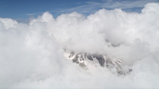 AX52_057 - 5K aerial stock footage of snowy slopes of Mount St. Helens peeking through cloud coverage, Washington