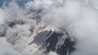 AX52_059 - 5K aerial stock footage orbit thick clouds to reveal snow on Mount St. Helens' slopes, Washington