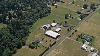 AX52_082 - 5K stock footage aerial video tilt to bird's eye view of farmhouse and barns beside country road in La Center, Washington