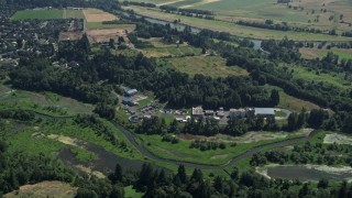 AX52_092 - 5K aerial stock footage approach and tilt to a water treatment plant beside a river in Ridgefield, Washington