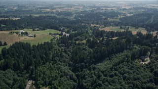 AX52_107E - 5K aerial stock footage fly over forest, rural homes and small farms around a country road in Hillsboro, Oregon