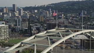 AX53_082 - 5K aerial stock footage of approaching American flag atop Fremont Bridge and pan to reveal Downtown Portland, Oregon