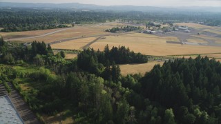 AX53_107 - 5K stock footage aerial video of flying over trees by warehouse toward Hillsboro Airport, Hillsboro, Oregon