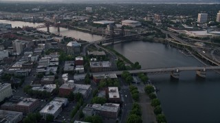 AX54_044 - 5K aerial stock footage of flying by bridges spanning the Willamette River near Memorial Coliseum and Moda Center, Downtown Portland, Oregon, sunset