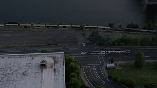AX54_046 - 5K aerial stock footage of approaching Broadway Bridge, and track a commuter train, North Portland, Oregon, sunset